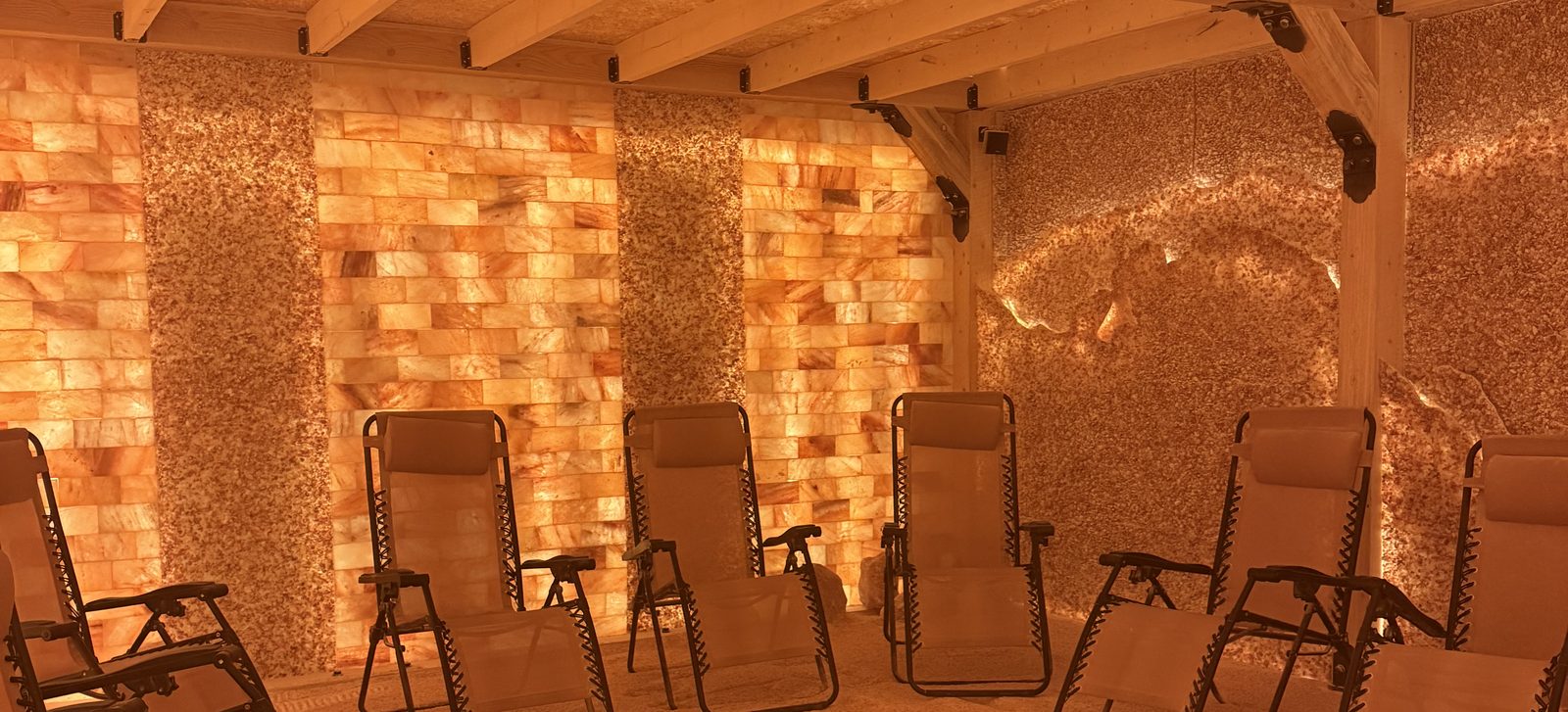 The Himalayan salt room at Colorado Salt Cave Wellness Center, lined with backlit salt brick and lounge chairs